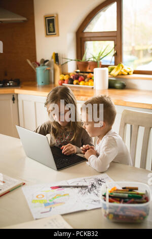 Children using laptop together in kitchen Stock Photo