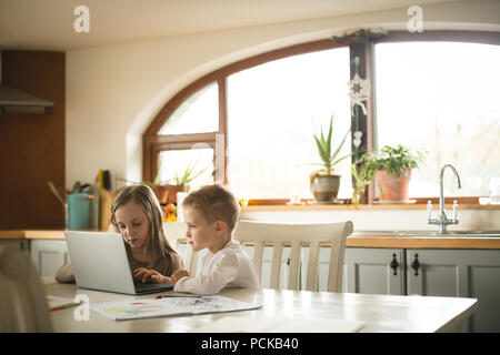 Children using laptop together in kitchen Stock Photo
