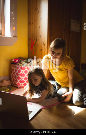 Mother and daughter using laptop in bedroom Stock Photo