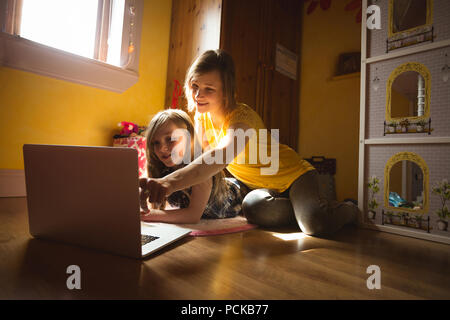 Mother and daughter using laptop in bedroom Stock Photo