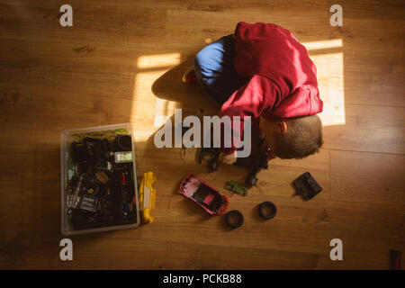 Little boy repairing toy car in bedroom Stock Photo