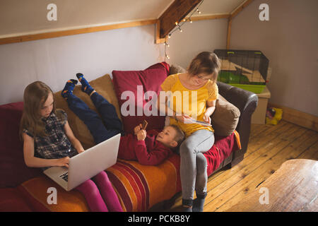 Family on sofa using multimedia devices Stock Photo