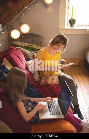 Family on sofa using multimedia devices Stock Photo
