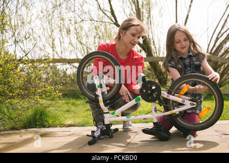 Mother and daughter repairing bicycle together Stock Photo