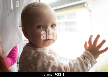 Mother with her baby girl looking through window Stock Photo