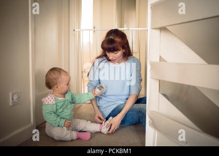 Mother helping her baby girl in wearing shoes Stock Photo