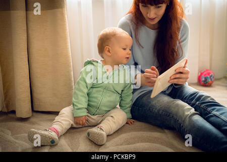 Mother showing her baby girl a digital tablet Stock Photo