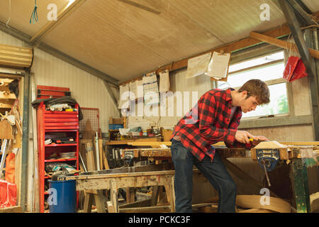 Male carpenter using plane tool in workshop Stock Photo
