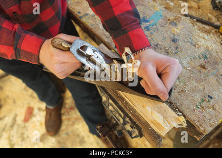 Male carpenter using plane tool in workshop