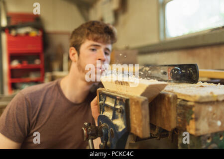 Male carpenter blowing wood shavings in workshop Stock Photo