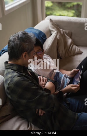 Father and son using digital tablet in living room Stock Photo
