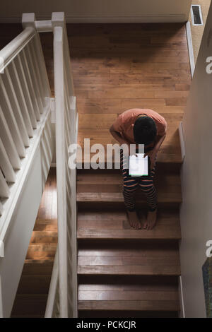 Boy using digital tablet on stairs Stock Photo