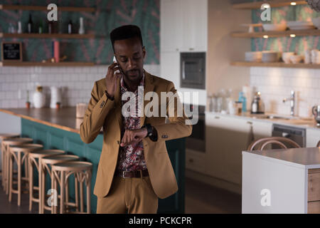 Businessman looking at smart watch while talking on mobile phone Stock Photo