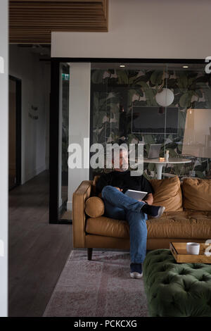 Thoughtful businessman using digital tablet on sofa Stock Photo