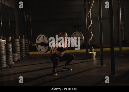 Woman lifting with barbell in gym Stock Photo