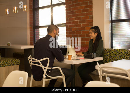 Business colleagues interacting with each other in cafeteria Stock Photo