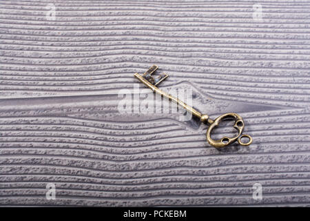 Retro styled decorative key placed on wooden texture Stock Photo