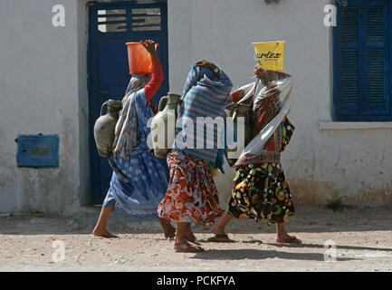 Tunisian Arab Berber women on their way to the Tozeur oasis to collect water in their amphora clay vessels Stock Photo