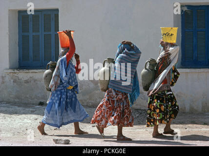 Tunisian Arab Berber women on their way to the Tozeur oasis to collect water in their amphora clay vessels Stock Photo