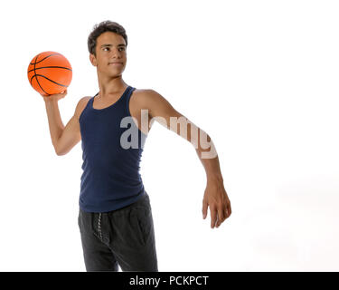 Portrait of a young basketball player passing the ball. Young caucasian boy in sportswear playing basketball on white background with copyspace Stock Photo