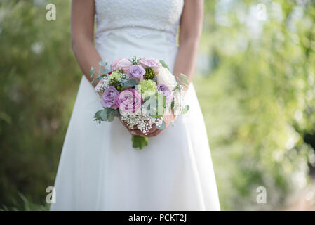 Wedding bouquet - Beautiful flowers in bride's hands in a white dress. Stock Photo