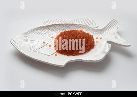 Red salmon caviar on a fish-shaped plate, isolated on white Stock Photo