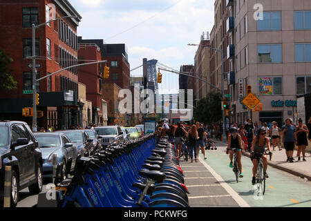 People dock CitiBike bicycles as cyclists pass on an adjacent bike lane next to Smorgasburg in Williamsburg, Brooklyn on JULY 8th, 2017 in New York, U Stock Photo