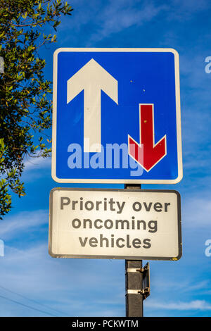 Priority over oncoming vehicles traffic sign against blue sky in England, UK Stock Photo