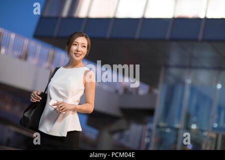Cheerful Chinese businesswoman walking outside a building Stock Photo