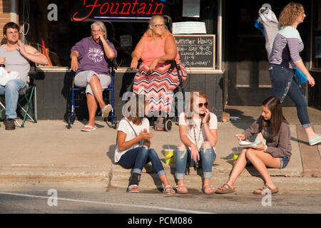 People waiting for the annual 2018 Cruz-In parade of antique and vintage vehicles through Montague, Michigan. Stock Photo