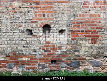 Fragment of the old red  brick fortress wall with loopholes for shooting from muskets and crossbows. Historical background Stock Photo