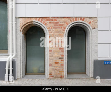 Two plastic arched windows in a red  brick wall of an old restored house Stock Photo