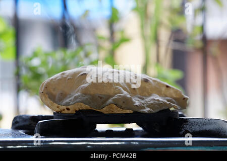 Phulka a kind of Chapati: home made Indian thin bread being cooked on gas stove at home, Mumbai, India. Stock Photo