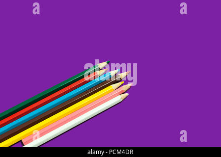 line of colored pencils lying diagonally on a purple background. concept of office and educational chancery. free space for advertising text Stock Photo