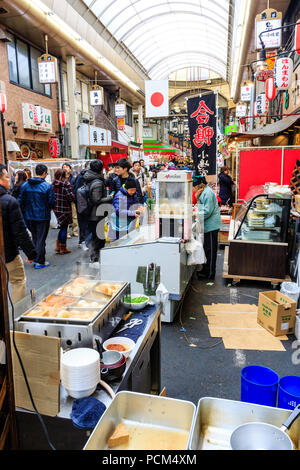 Kuromon Ichiba, Osaka's kitchen food market. View along arcade with stall in foreground selling oden, typical winter food. Market crowded with people. Stock Photo