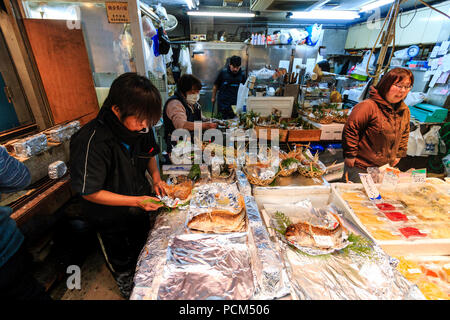 Kuromon Ichiba, Osaka's kitchen food market. Fish mongers, interior, sea beams being prepared by staff for display and sale. Other fish displayed. Stock Photo