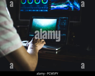 young man edit video in dark studio using color grading tools and modern equipment Stock Photo