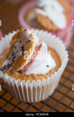 Homemade vanilla cupcakes with a chocolate coated strawberry and icing. Stock Photo