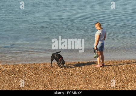 Thorpe Bay, Southend-on-Sea, Essex, UK. 3rd August, 2018. UK Weather: Morning views on the beach at Thorpe Bay - a view of a Woman & her dog Credit: Ben Rector/Alamy Live News Stock Photo