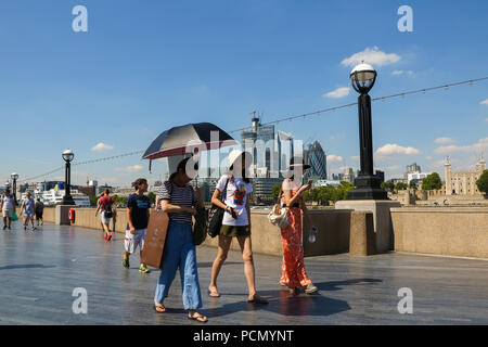 Potters Fields Park. London. UK 3 Aug 2018 - Tourists shelter from the sun beneath and umbrella and hats on another very hot day in the capital. According to the Met Office the heatwave is to continues in the UK and parts of Europe in coming days with record temperatures expected.  Credit: Dinendra Haria/Alamy Live News Stock Photo