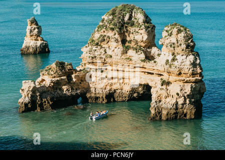 Beautiful views of the Atlantic Ocean off the coast of Portugal near the city of Lagos. A sea boat sails along the blue or turquoise water. Stock Photo