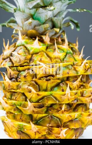 Close-up of sliced pineapple on white and grey background. Front view of creatively cut  ripe fresh pineapple Stock Photo