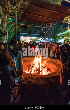 Shogatsu, new year, Nishinomiya shrine, Japan. People standing around bonfire used to burn old good luck charms, during their first visit, Hatsumode. Stock Photo