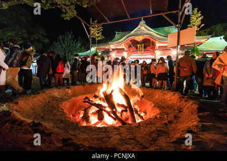 Shogatsu, new year, Nishinomiya shrine, Japan. People standing around bonfire used to burn old good luck charms, during their first visit, Hatsumode. Stock Photo