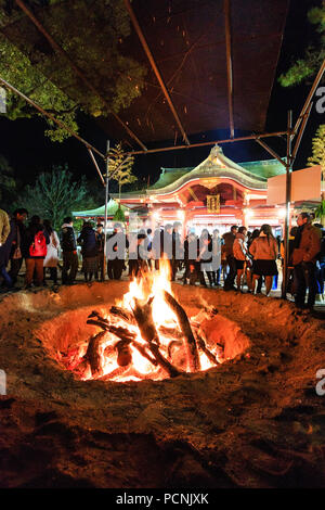 Shogatsu, new year, Nishinomiya shrine, Japan. People standing around bonfire used to burn old good luck charms, during their first visit, Hatsumode. Stock Photo