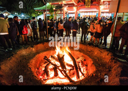 Shogatsu, new year, Nishinomiya shrine, Japan. People standing around bonfire used to burn old good luck charms, during their first visit, Hatsumode. Stock Photo