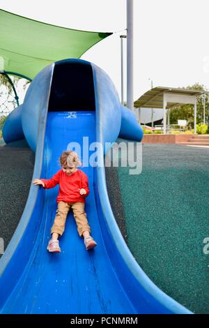 A child goes down a blue slide designed like a dugong, Cardwell, Queensland, Australia Stock Photo