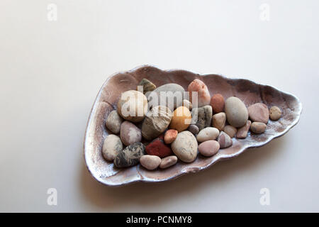 Sea stones with various colors and shapes in seashell isolated on white background Stock Photo