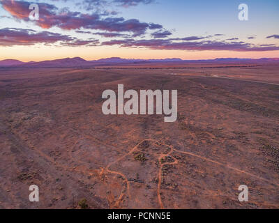 Desert land and Flinders Ranges peaks in the distance at dusk - aerial view Stock Photo