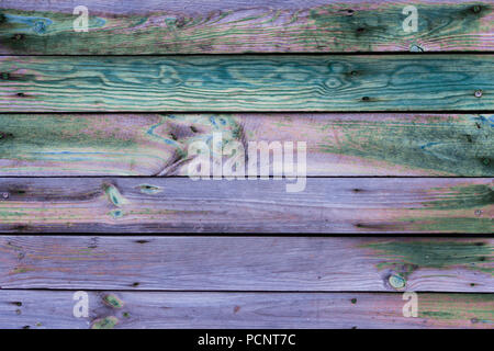 Close-up of the multicolor surface (wall, floor or overhead) made of wooden plank, panel or board in the purple, turquoise, blue, pink, green shades Stock Photo